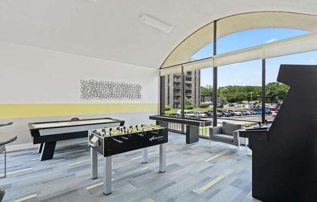 A billiard table is in the middle of a room with a black sofa and a black chair.
