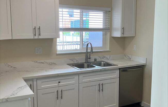 A kitchen with white cabinets and a marble countertop.