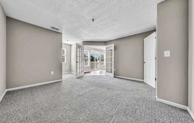 an empty living room and hallway with doors to a patio