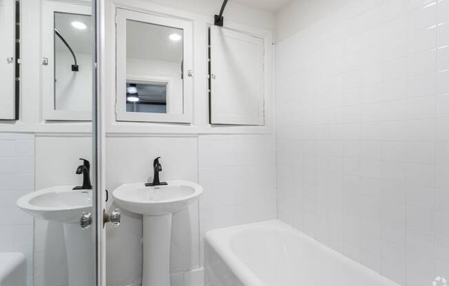 a white bathroom with two sinks and a tub and a shower