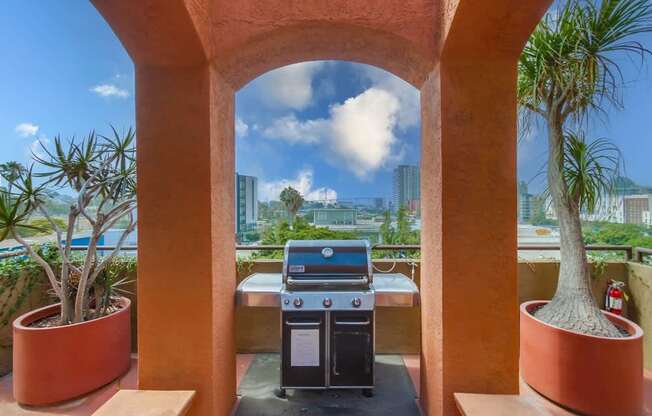 A BBQ grill is in the middle of a patio with a view of the city.