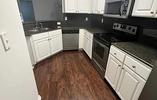 a large kitchen with wooden floors and white cabinets