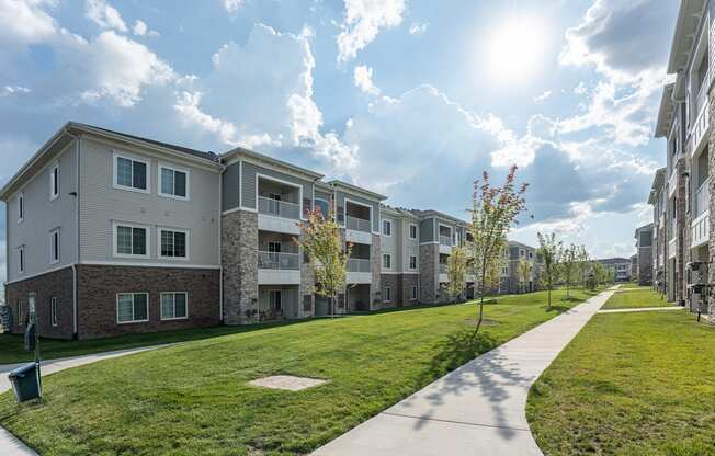 Exterior view of community, paved sidewalk through green grass.