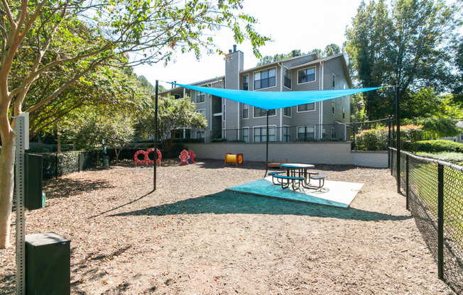 a playground with a swing and picnic table in front of a house