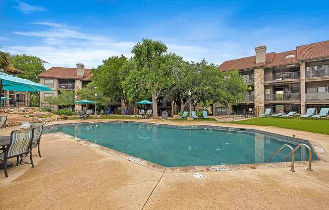 a resort style pool with lounge chairs and umbrellas at homewood suites by h