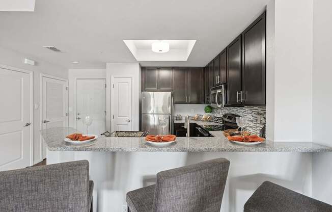 A modern kitchen with a dining table set for two.