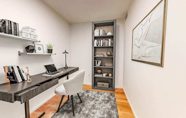 a home office with a desk with a laptop and a book shelf