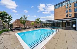 A swimming pool in a sunny outdoor area with a building in the background.