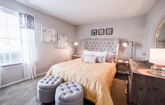 Bedroom with a window and neutral colored walls at Chelsea Village Apartments