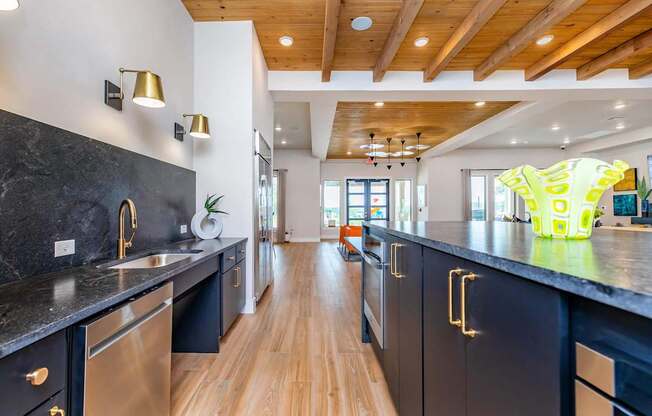A modern kitchen with black cabinets and a wooden ceiling.