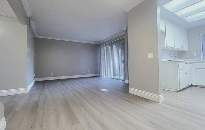 an empty living room and kitchen with wood flooring