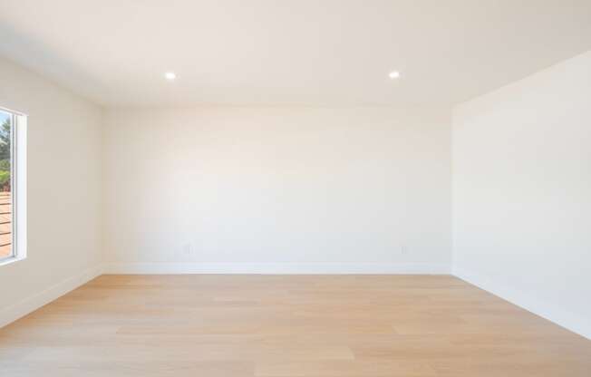 an empty room with white walls and wood floors