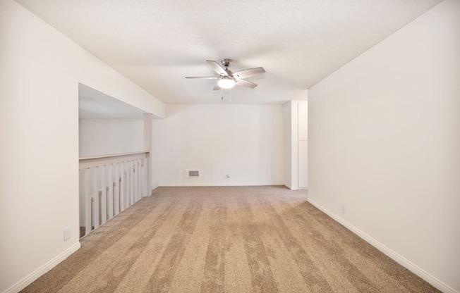 an empty living room with white walls and a ceiling fan