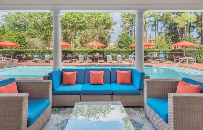 a poolside lounge area with blue couches and orange pillows at Sterling Manor, Williamsburg, VA