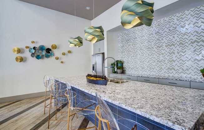 A modern kitchen with a marble countertop and gold chairs.