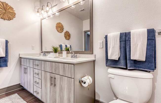 A bathroom with a white toilet and a white sink with a mirror above it.