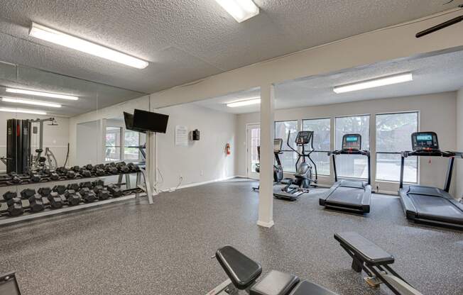 a gym with treadmills and other exercise equipment and windows