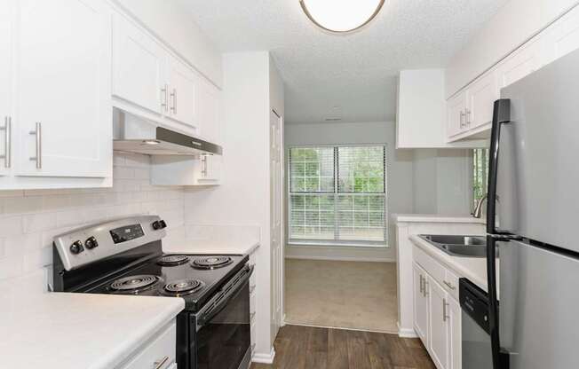 A kitchen with white cabinets and black appliances.