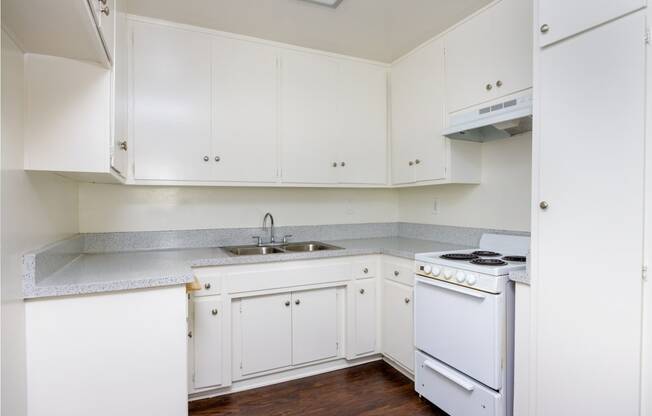 a kitchen with white cabinets and white appliances and a sink