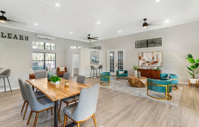 A room with a dining table and chairs, a sofa, and a rug.