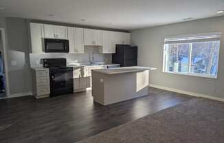an empty kitchen with white cabinets and black appliances