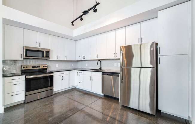 A kitchen with white cabinets and a stainless steel refrigerator.