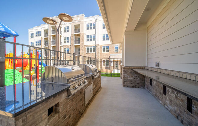 a patio with a grill and a building in the background