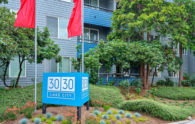 a large blue apartment building with two red flags in front of it  at 3030 Lake City, Seattle, Washington