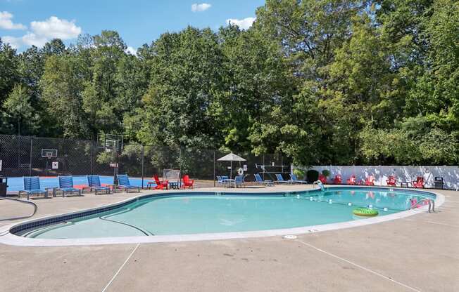 A large outdoor swimming pool surrounded by trees and a fence.