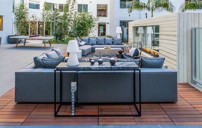 A modern outdoor seating area with a large grey sofa and a coffee table.