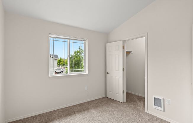 an empty bedroom with a window and a closet