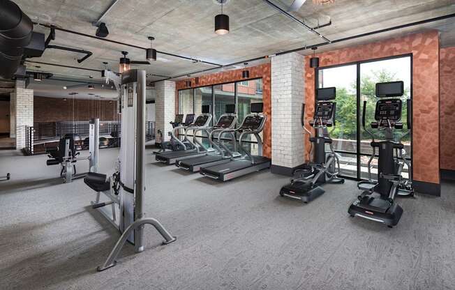 a gym with treadmills and other exercise equipment in a room with glass windows