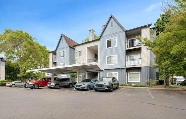 A grey apartment building with cars parked in front.