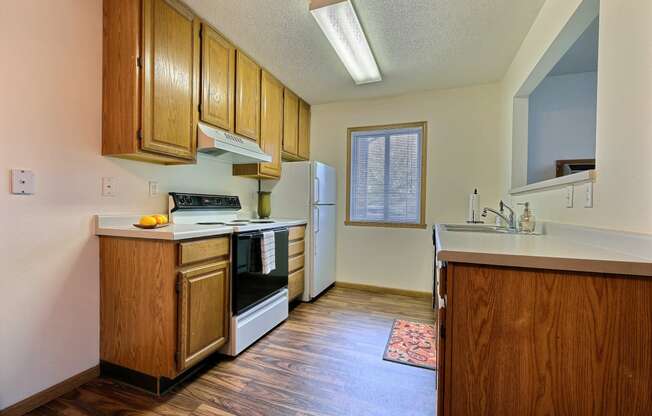 A kitchen with white appliances and wooden cabinets. Fargo, ND Oxford Apartments.