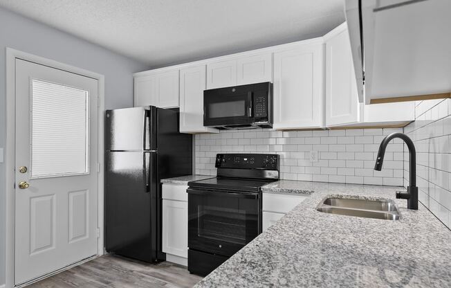 a kitchen with black appliances and white cabinets