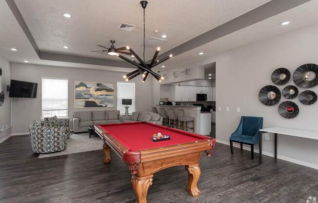 A pool table is in the middle of a room with a ceiling fan and a chair.