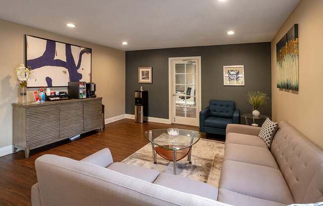 A living room with a grey couch and a glass coffee table.