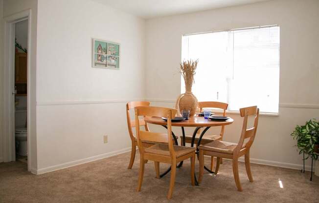 A dining room with a table and chairs at North Village Apartments in Kansas City, MO.