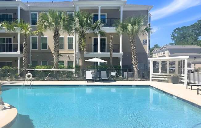 a large swimming pool in front of a building with palm trees