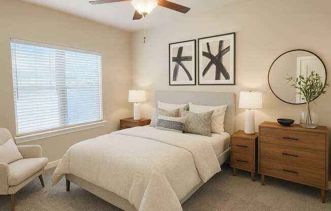 A bedroom with a bed, chair, and two lamps.