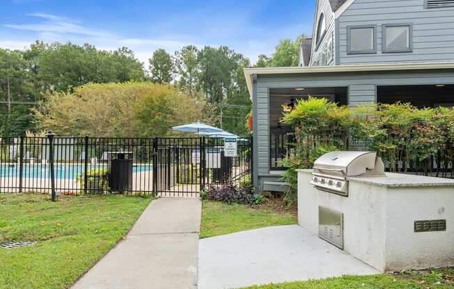 the backyard of a house with a grill and a sidewalk and a swimming pool