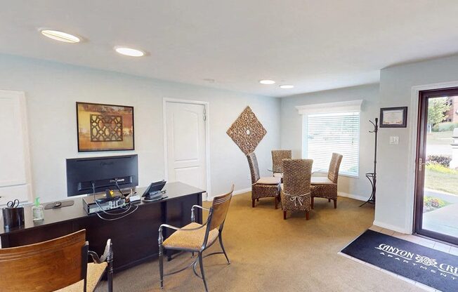 a living room with a desk and chairs and a television