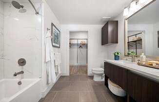 Modern bathroom with dual vanity, soaking tub, and direct walk-in closet access
