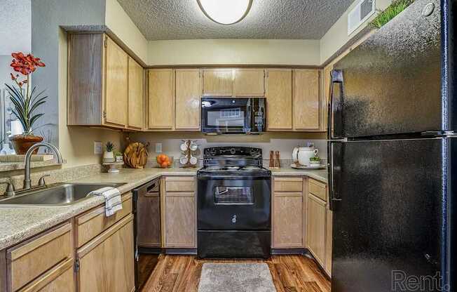 A kitchen with wooden cabinets and a black refrigerator.