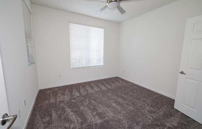 an empty room with carpet and a ceiling fan