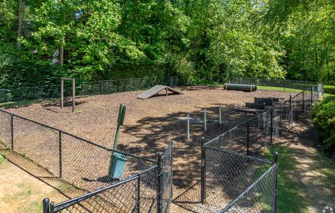 a fenced in dog park with a    and trees