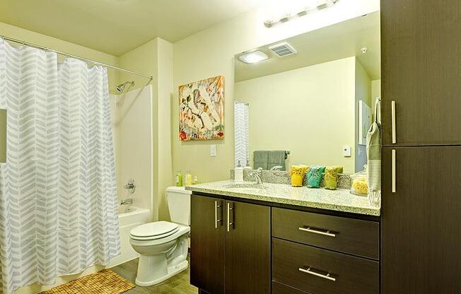 A bathroom with a toilet, sink, and shower curtain. at Kirkland Crossing Apartments, Kirkland, Washington