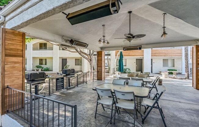 A patio with a table and chairs is covered by a roof.