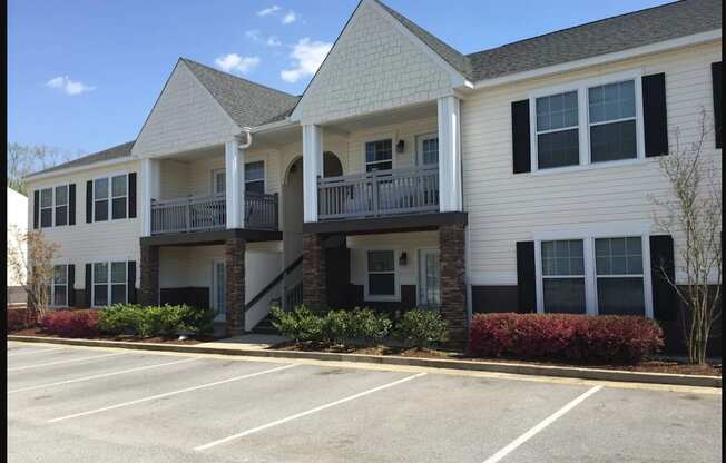 A white building with a parking lot in front.