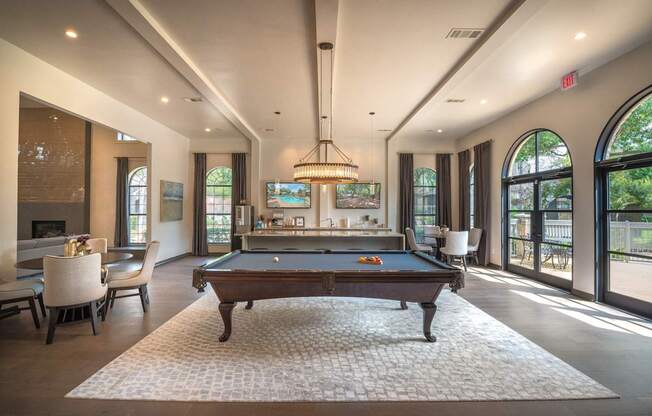 A pool table is in the middle of a room with a chandelier hanging from the ceiling.